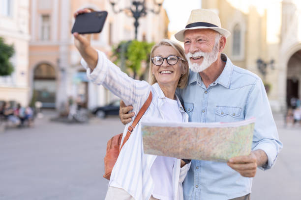 istock Elderly couple smiling and taking a selfie with map during travel. 2166586651