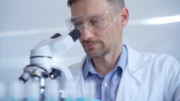istock Man scientist with protective glasses and gloves is using microscope in laboratory, portrait of researcher. Microbiology science concept 2166587080