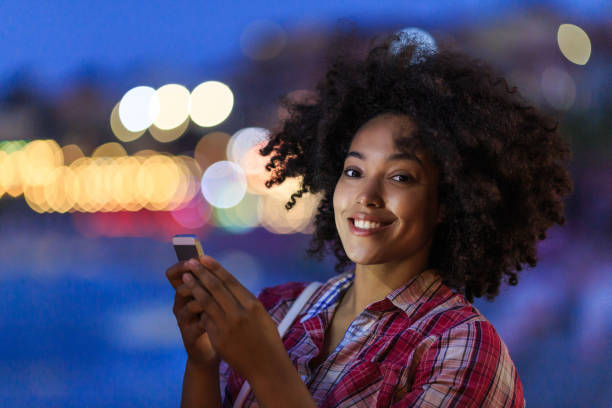 istock Happy woman with phone on urban night backdrop 2166588175