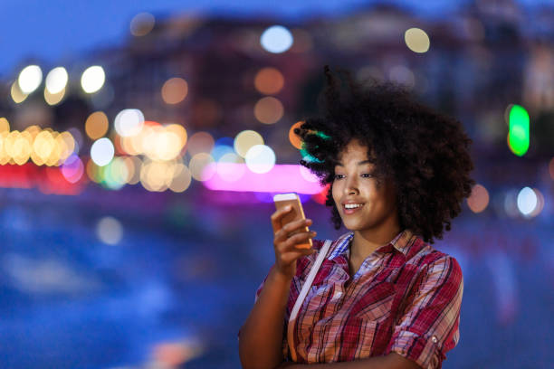 istock Smiling woman using phone with city lights behind 2166588181