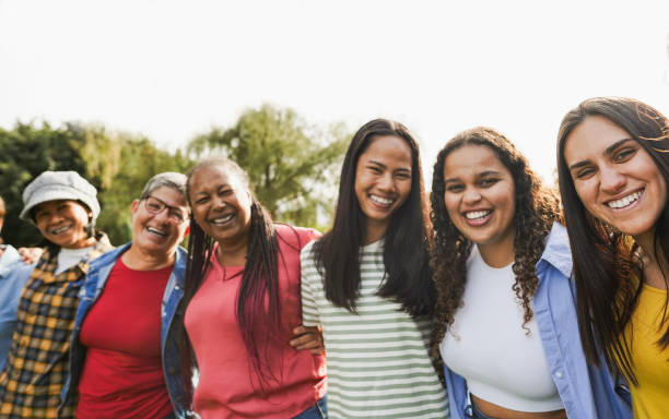 Multi generational women smiling in front of camera - Female multiracial group having fun togheter outdoor - Main focus on right girl face