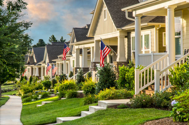 Patriotic Neighborhood American Flags hang from the front of this traditional, brick homes in an All-American neighborhood. small town america stock pictures, royalty-free photos & images