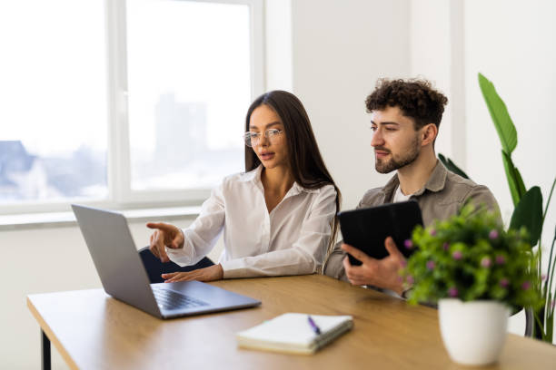 istock Two businessworkers smiling happy working sitting on desk at the office. 2166593110