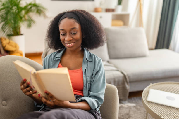 istock Happy woman immersed in her book on a cozy sofa 2166593180