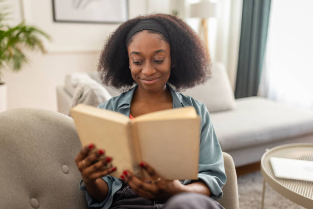istock Joyful woman reading a book on comfortable living room 2166593849