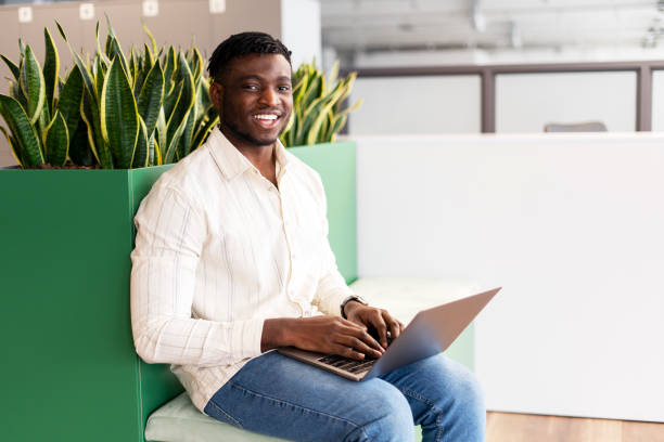 istock Young black man smiling working on laptop in modern office 2166594282