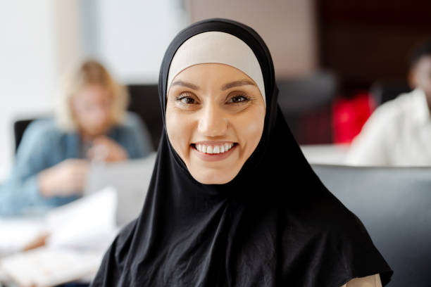 istock Young muslim woman smiling while working in busy office looking at camera 2166594321