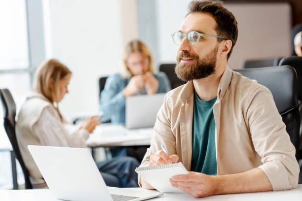 istock Smiling, happy manager taking notes during meeting with creative team in office 2166594358