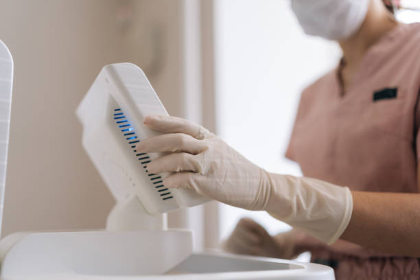 istock Close-up cropped shot of unrecognizable dermatologist in rubber gloves setting modern device in medical clinic. Closeup hands of female doctor adjusting apparatus 2166598034