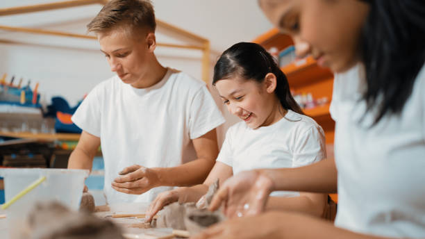 istock Handsome student dipping hand in to water to soften clay at class. Edification. 2166600189