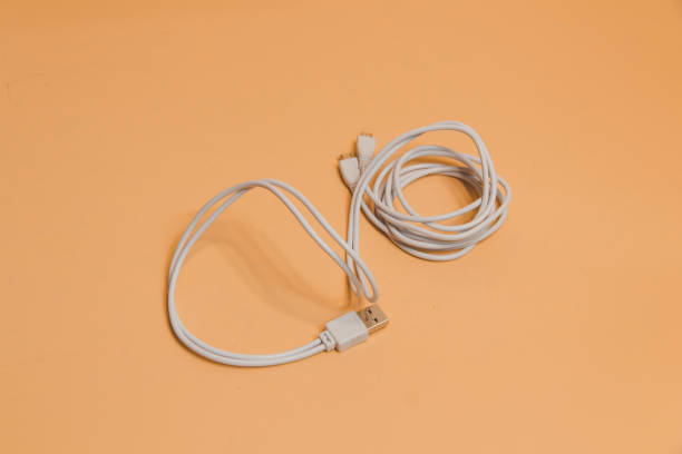 istock USB cable for smartphone on beige background, White usb cable on beige background, computer peripherals connector or smartphone recharge supply 2166600317