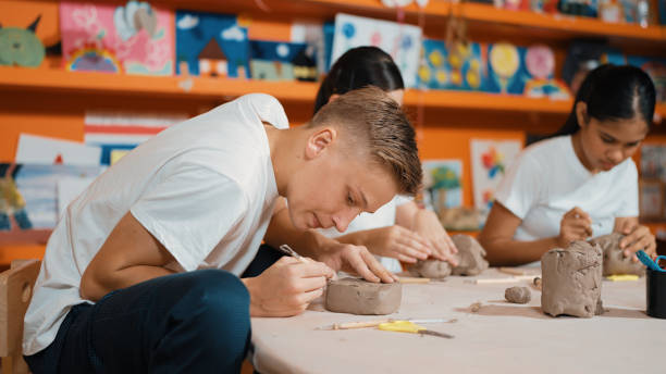 istock Teenager using carving tool working at clay at pottery workshop. Edification. 2166602116