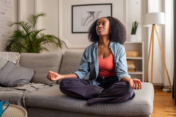 istock Woman meditating sitting cross-legged on couch 2166602865