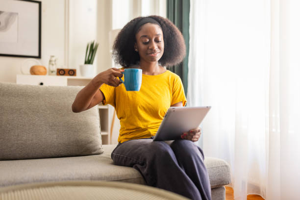 istock Woman smiling and drinking from blue mug with tablet. 2166605370