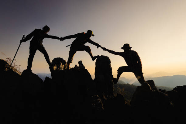 istock Silhouette of a group of climbers on a mountaintop. Success, teamwork and unity. 2166605551