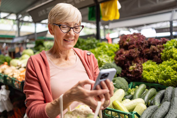 istock Elderly shopper checking phone among vegetables 2166606743