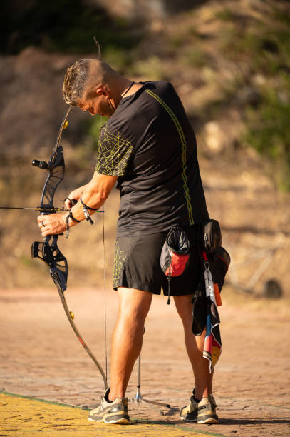 istock A man is standing in a field with a bow and arrow 2166608159