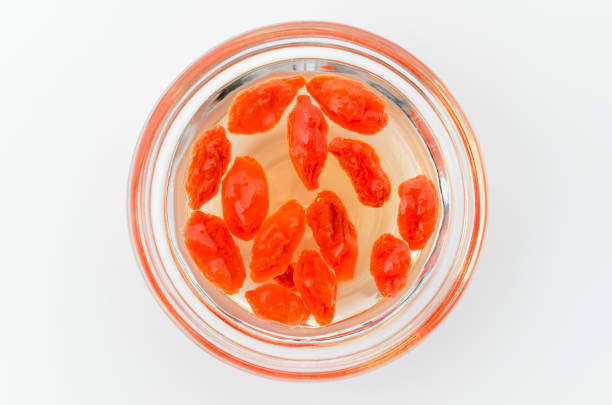 Soaked Goji berries in water in a white bowl on white background