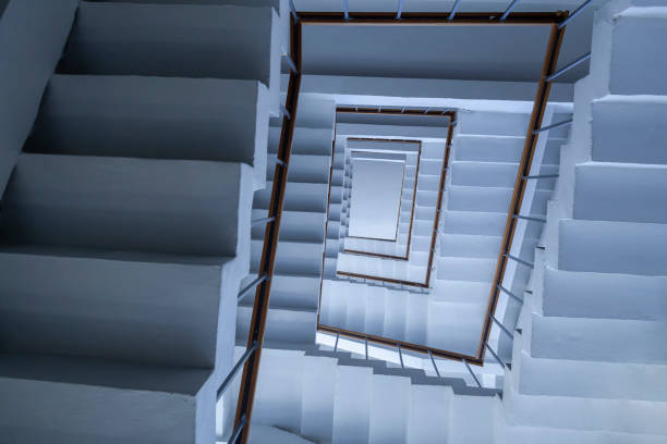 Abstract view of a spiral staircase with a blue tint, emphasizing the modern architectural design and symmetry.