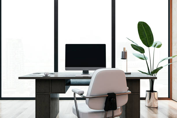 istock Modern office desk with computer, chair, and plant in front of large windows. 3D Rendering 2166610255