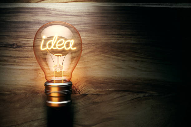 Illuminated lightbulb with the word idea glowing inside, standing against a wooden background. Concept of creativity and innovation. 3D Rendering
