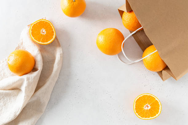 istock Paper shopping bag with organic oranges on white background. Flat lay, top view. Zero waste, plastic free concept. Healthy clean eating diet and detox. Summer fruits. Delivery, online shopping concept 2166611409