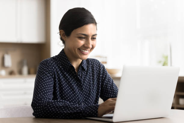istock Happy woman using laptop sitting at table in the kitchen 2166611744