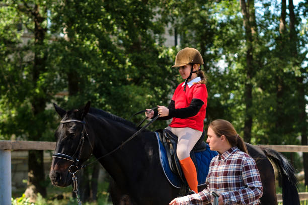 Young rider focuses on handling reins with instructor. Riding school