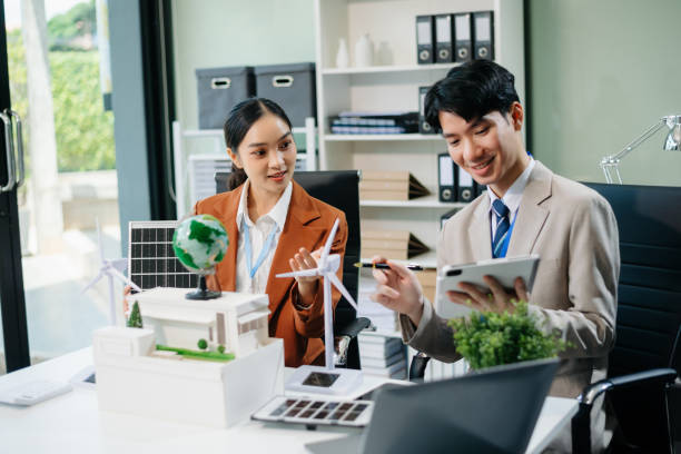 istock Young professionals for a greener future. Showcasing renewable energy solutions with solar panels, wind turbines, and a model house. 2166614261