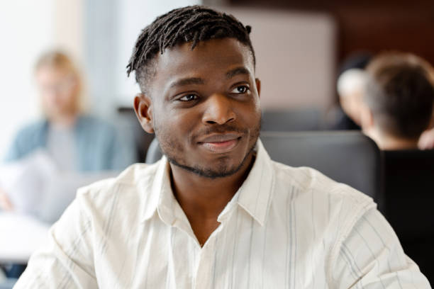 istock Young professional smiling while working in busy open plan office looking away 2166615201