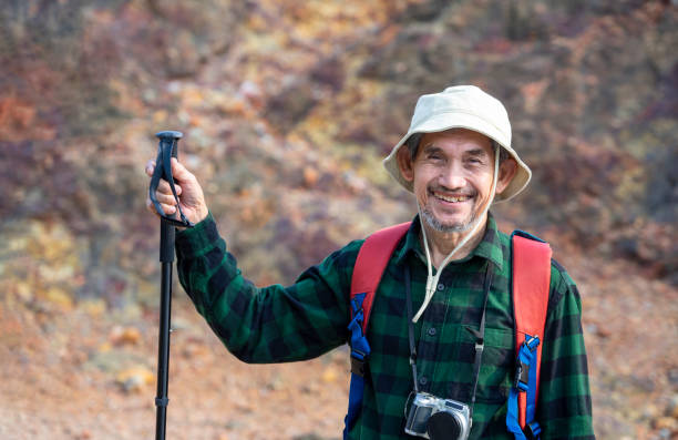 istock senior man in checkered shirt wears hat,having a camera,carry backpack,holds trekking pole for climbing the mountain,elderly lifestyle,travel,hiking,adventure 2166623002