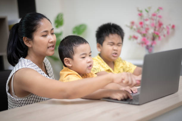 istock A mother and her two young sons happily engage with a laptop, exploring technology together in a bright, cozy home setting. 2166626751