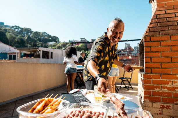 Mature man doing barbecue with friends on rooftop