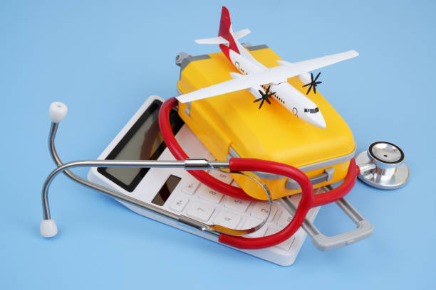 istock Airplane model, calculator and stethoscope with orange suitcase on blue background. 2166632652