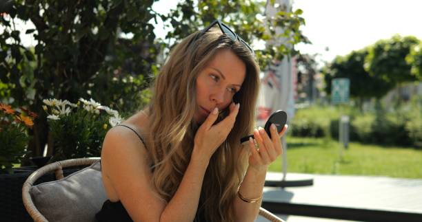 istock Focused woman adjusts eyes makeup looking in small mirror 2166633123