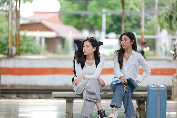 istock Two women sitting on a bench at a train station 2166633348