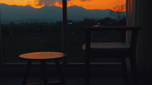 istock Cozy evening scene with chair and table silhouetted against vibrant 2166633444