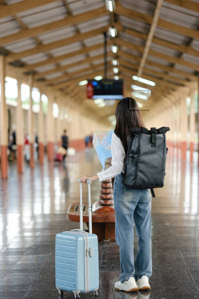 istock A woman is standing in a train station with a suitcase and a map 2166633448