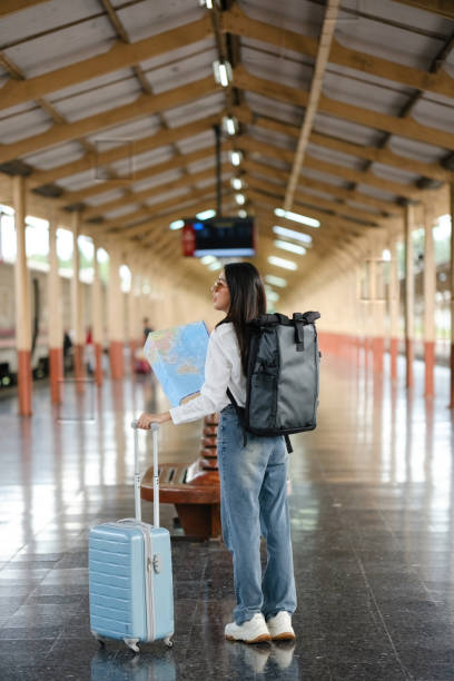 istock A woman is standing in a train station with a suitcase and a backpack 2166633458
