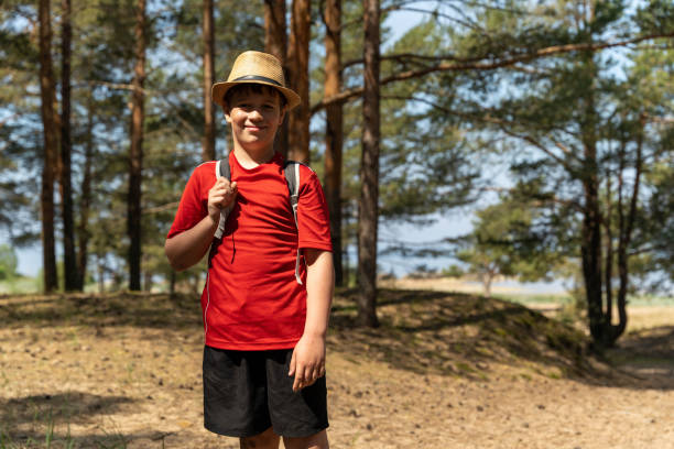 istock Boy smiles at camera hiking in forest on sunny day with straw hat 2166633582