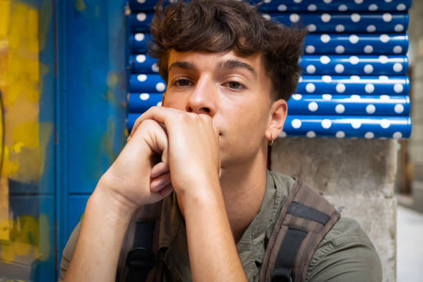 Close-up of tired student take nap behind pile of textbooks on table. Sleepy man resting during education after sleepless night. Despair, deadline concept