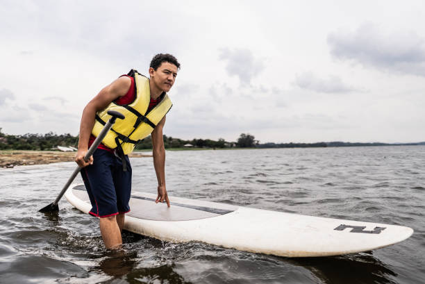 istock Young man paddleboarding in a lake 2166639983