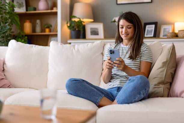 istock Woman comfortably using her smartphone on a sofa. 2166640653