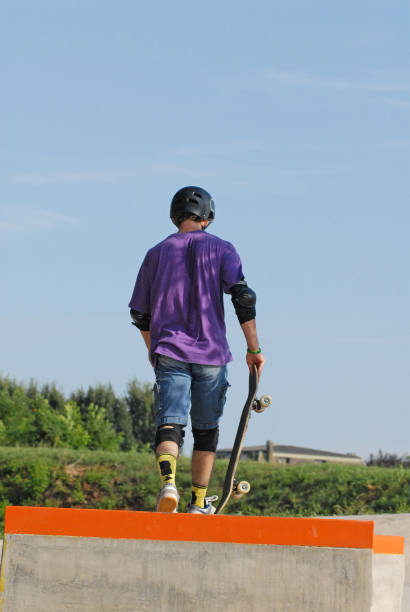skateboard boy walking away holding his skateboard.
