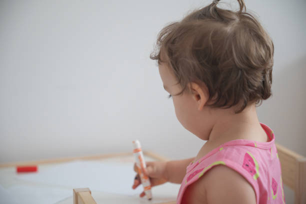 Happy little girl showing her art drawing imagination with colorful crayon on white paper for school homework, childhood painting art playing creativity and inspiration kids artwork learning at home.