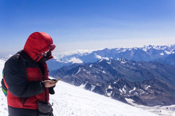 mountain climber looking at smartphone screen while standing on highland snow slope