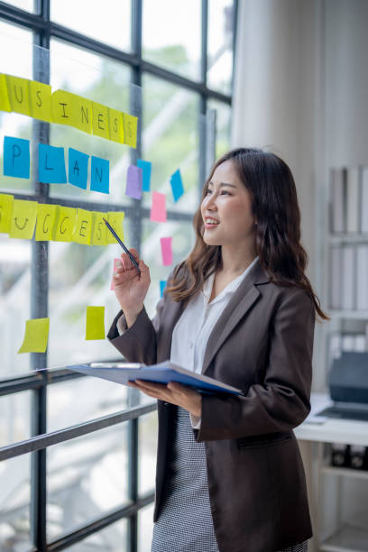istock A woman is standing in front of a board with yellow and pink post it notes 2166644525
