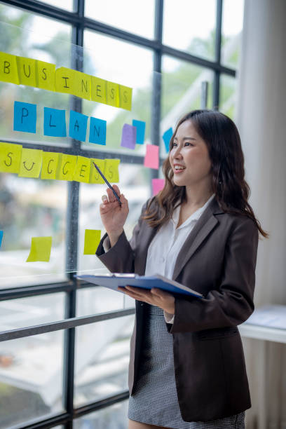 istock A woman is standing in front of a board with yellow and blue post it notes 2166644551