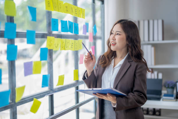istock A woman is standing in front of a whiteboard with yellow and blue post it notes 2166644624