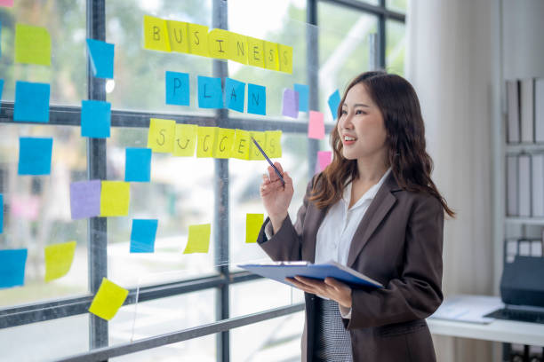 istock A woman is standing in front of a board with yellow and blue post it notes 2166644699
